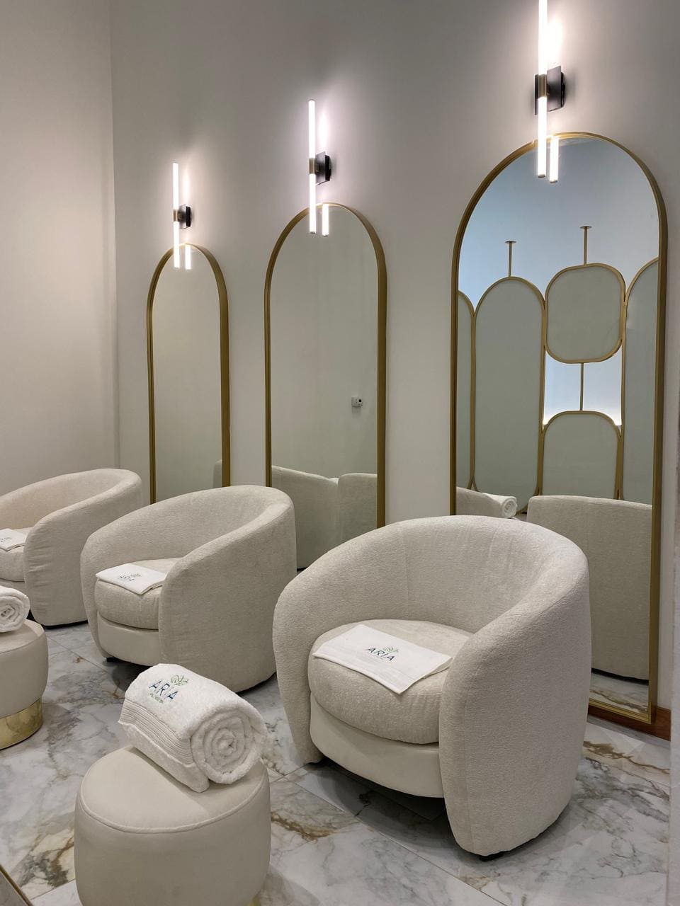 Sala de pedicura con sillones bouclé y espejos dorados
